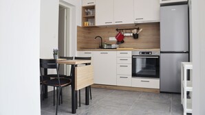 Una cocina moderna con armarios blancos, encimera de madera, horno empotrado y refrigerador de acero inoxidable.