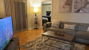 A living room with a flat-screen TV, a sofa, a coffee table, and a floor lamp.