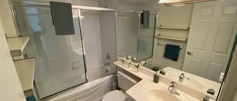 A modern bathroom with a glass-enclosed shower, a white toilet, a sink with a mirror, and a towel rack.