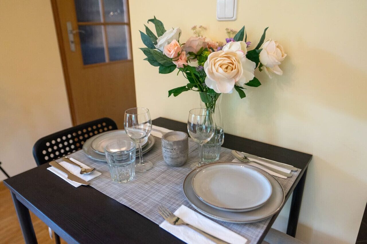 A dining table set with plates, glasses, and cutlery, a vase with flowers, and a salt and pepper shaker.