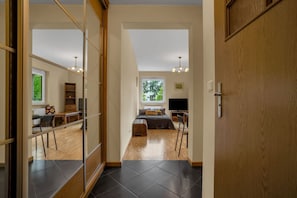 Een modern interieur met een houten vloer, een bank, een televisie en een eethoek met een tafel en stoelen.