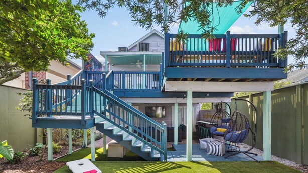 Een huis met twee verdiepingen, een blauwe trap, een hangstoel en een klein terras.