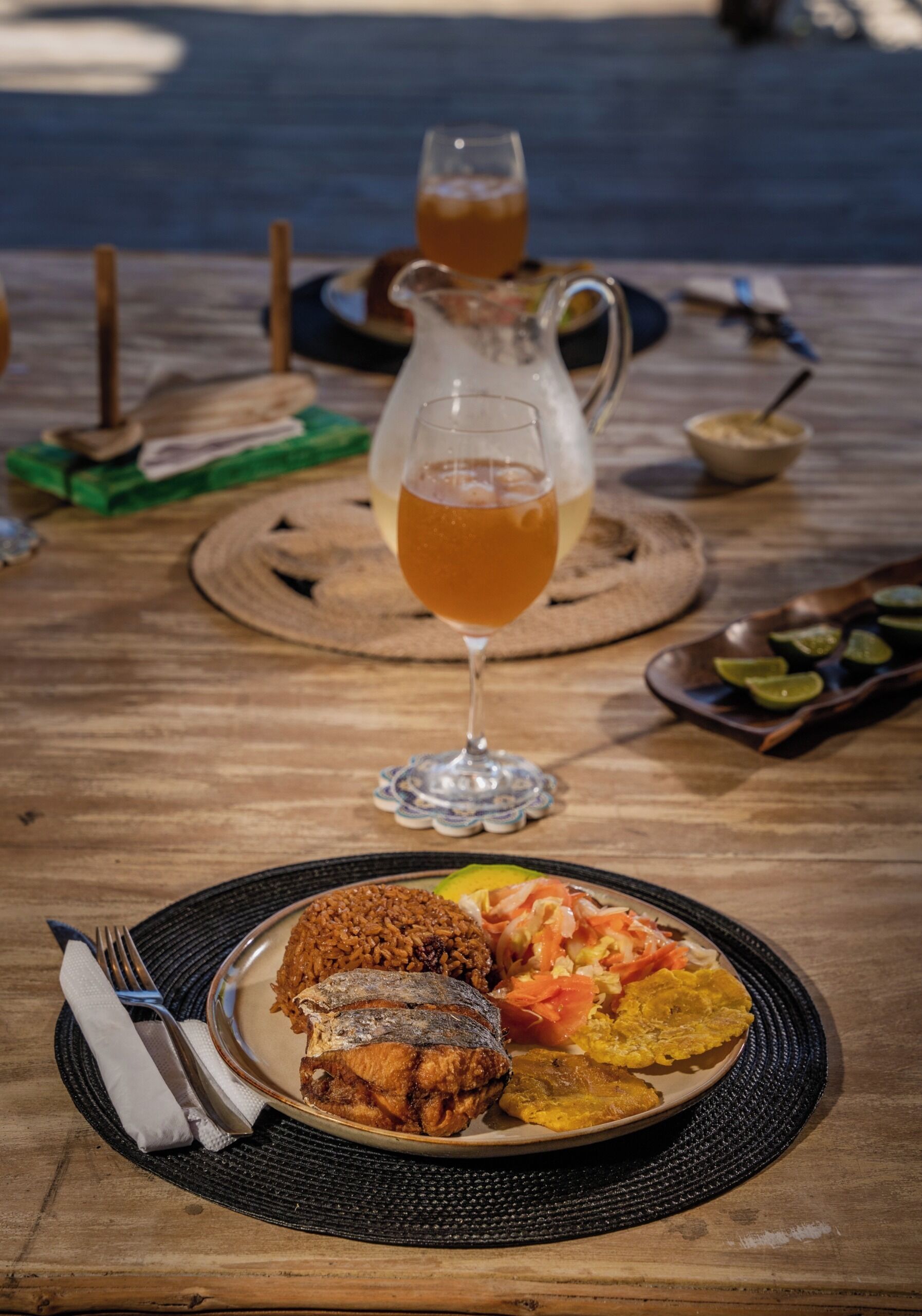 Una mesa de madera con un plato de comida, una jofaina de bebida y un vaso.