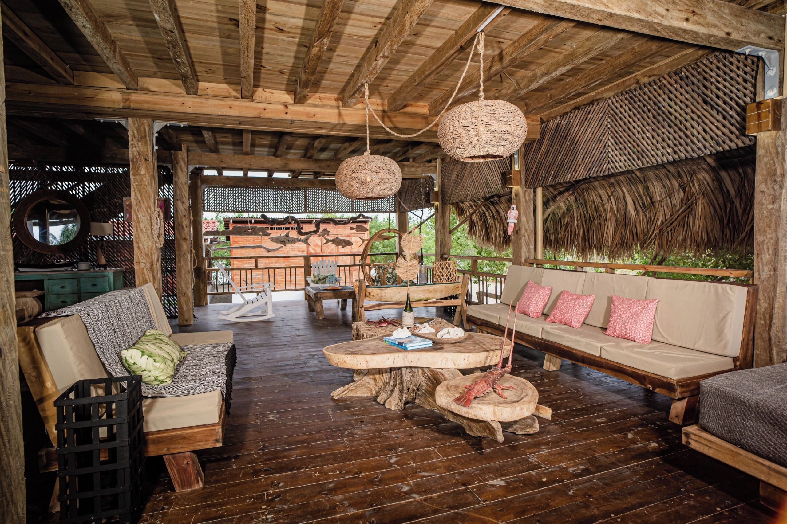 A rustic wooden interior with a thatched roof, wooden furniture, and a wooden table with a lobster centerpiece.