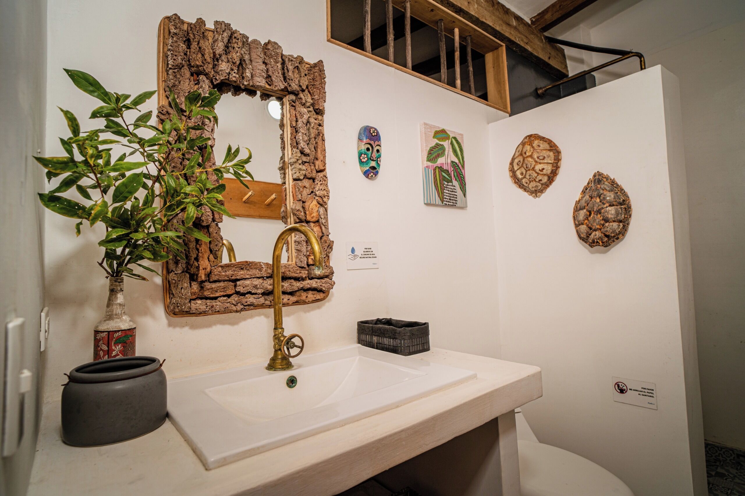 Un baño con un espejo rústico, un lavabo y decoración en la pared.