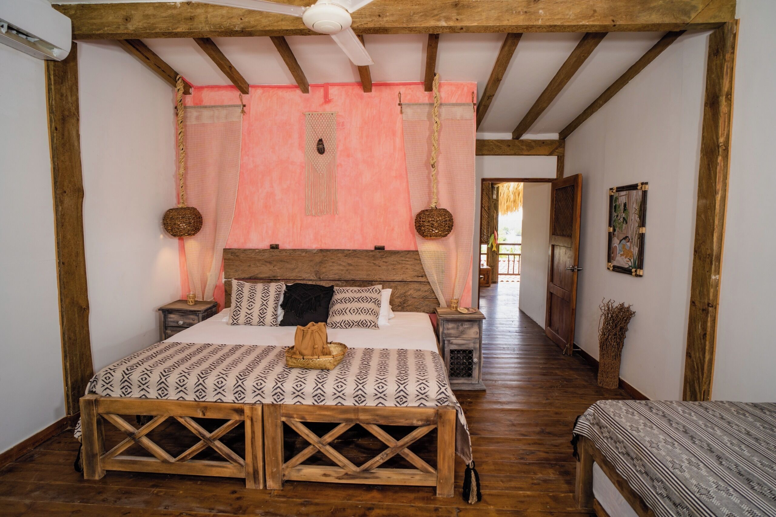 A bedroom with a wooden bed, a nightstand, a bedside table, a hanging basket, and a wooden bench.