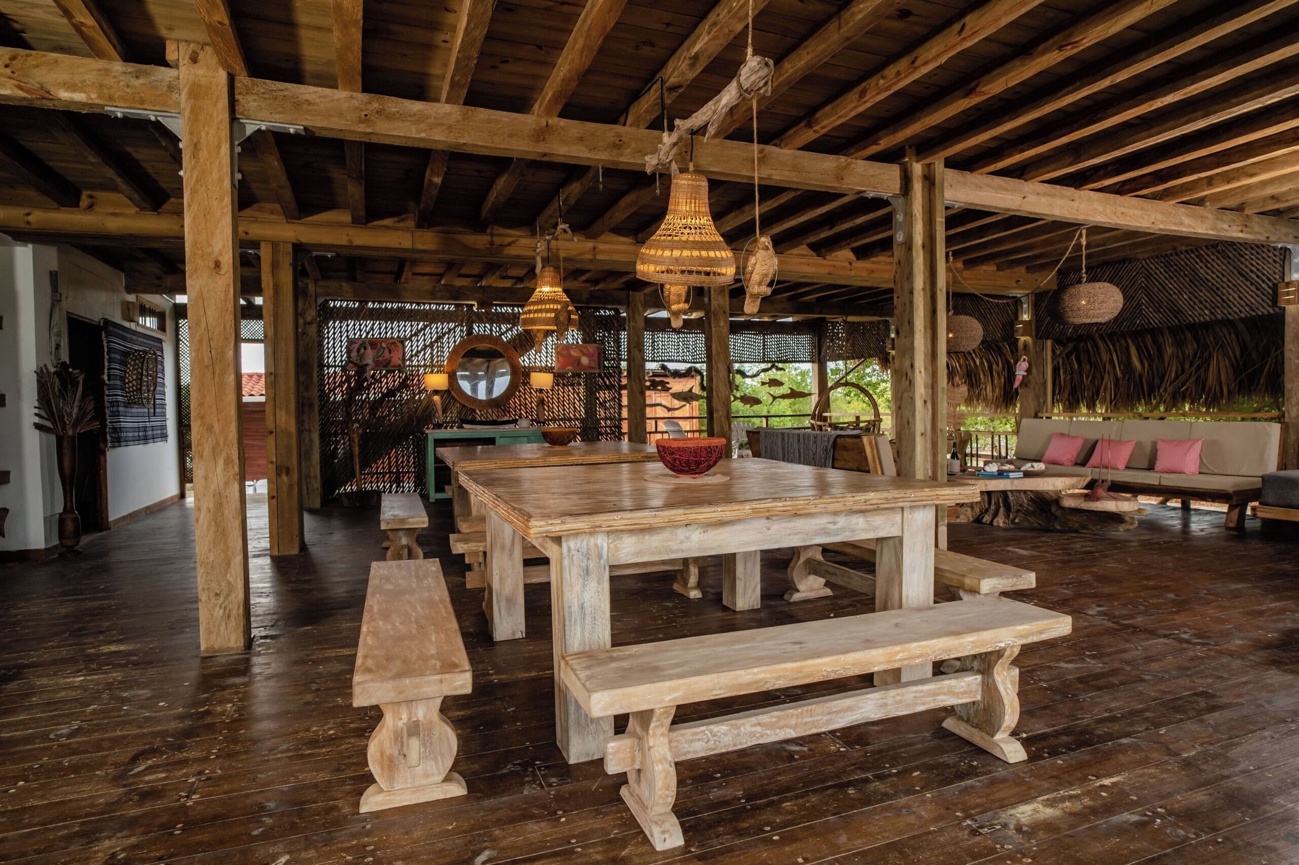 A rustic wooden dining area with benches and a table, surrounded by wooden beams and hanging light fixtures.