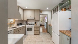 A compact kitchen with a stove, sink, and white refrigerator.