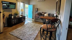 A living room with a TV, a ceiling fan, a dining area with a table and chairs, and a sofa. - Unit 2 Teal bungalow is pet-friendly for your stay. close to Galveston and Kemah (Bacliff)