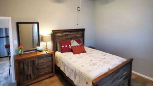 A bedroom with a bed, a nightstand, a dresser, a ceiling fan, and a mirror. - Unit 2 Teal bungalow is pet-friendly for your stay. close to Galveston and Kemah (Bacliff)