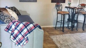 A living room with a sofa, a coffee table, and two chairs. There are two wall-mounted air conditioning units and two framed pictures. - Unit 2 Teal bungalow is pet-friendly for your stay. close to Galveston and Kemah (Bacliff)