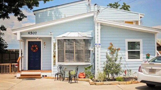 A light blue house with a dark blue door, number 4507, a small porch with a table and chairs, and a car parked in the driveway. - Unit 2 Teal bungalow is pet-friendly for your stay. close to Galveston and Kemah (Bacliff)