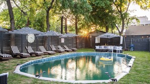 Ein Garten mit Schwimmbad, Liegestühlen und einer überdachten Sitzgruppe.