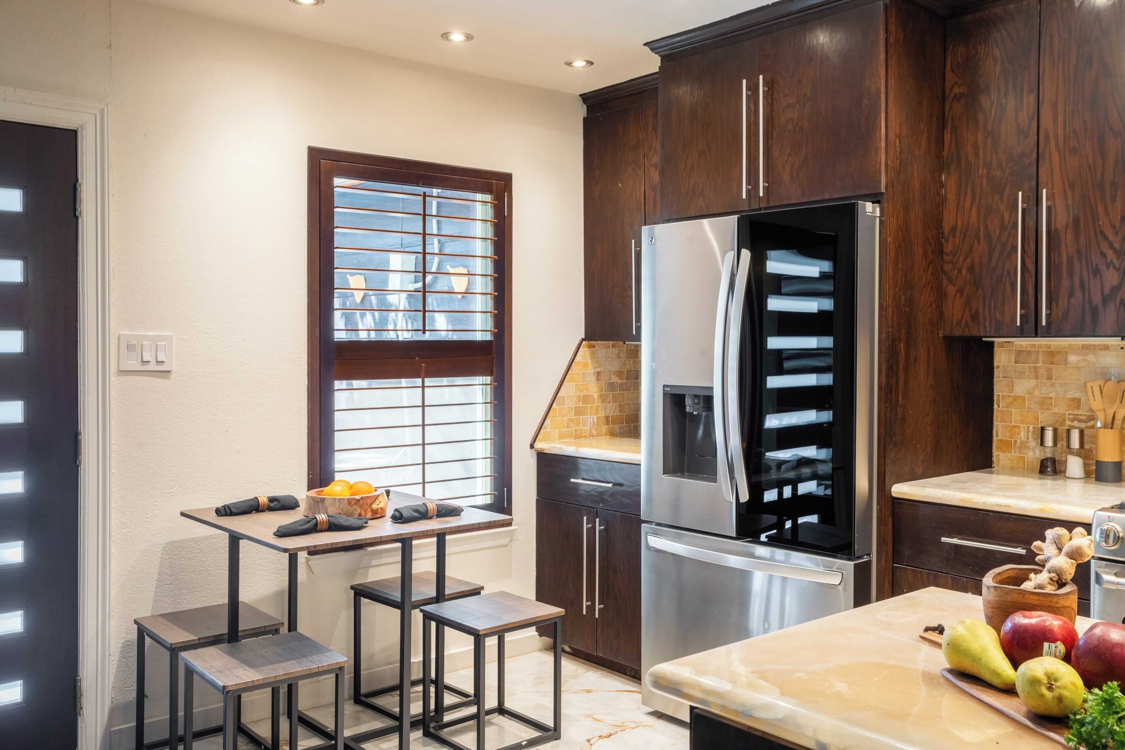 A modern kitchen with dark wood cabinets, stainless steel appliances, and a window with blinds.