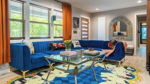 Ein Wohnzimmer mit einem blauen Sofa, einem Glastisch und einem Teppich mit Muster.