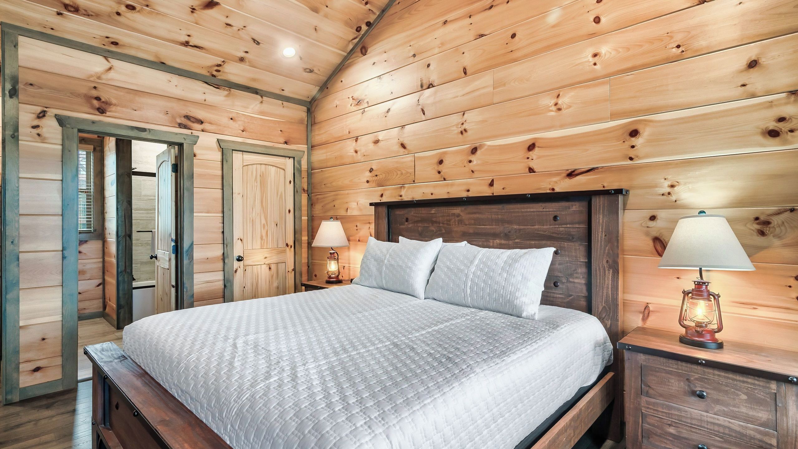 Ein Schlafzimmer mit Holzwänden, einem Bett, zwei Nachttischlampen und einem Nachttisch.