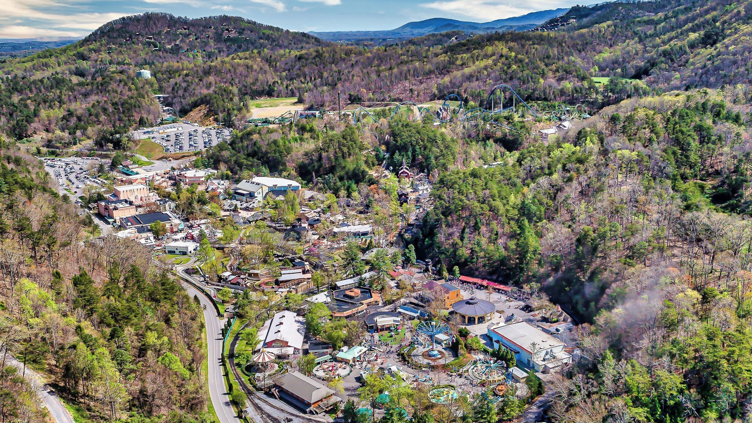Vista aérea de un pueblo con un parque central, una montaña rusa y un estacionamiento.