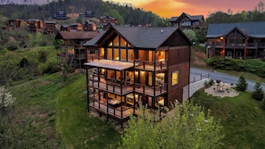 A multi-story wooden lodge with balconies, a deck, and a fire pit area. - Smoky Horizon by Avantstay Game Room, Movie Theater, Deck w Hot Tub Views! (Sevierville)