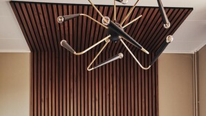 A modern bedroom with a slatted wooden headboard, a central ceiling light fixture, and two bedside lamps.