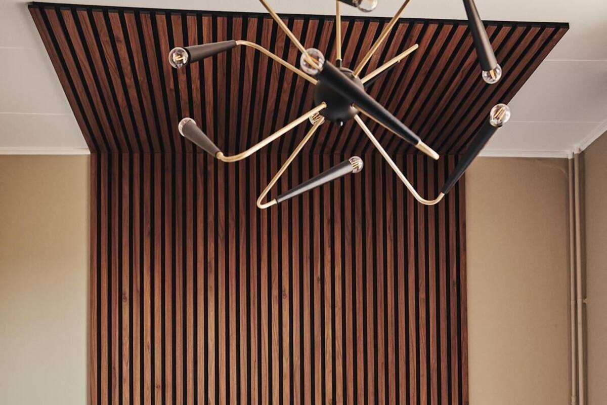 Un dormitorio moderno con un cabecero de madera con listones, una lámpara de techo central y dos lámparas de noche.