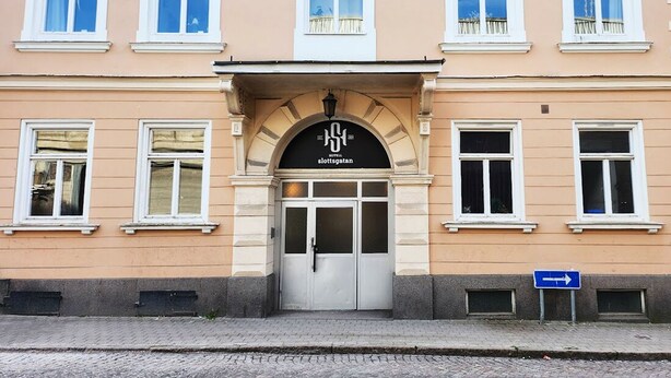 A building with a central entrance, multiple windows, and a sign above the door.