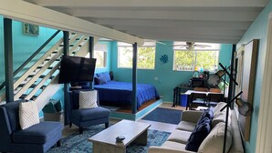 A spacious living room with a staircase, a bed, a TV, and a dining area. - Manta Suite w/ ocean view and sleeping 6 --TA-154-746-2656-01 (Kealakekua)
