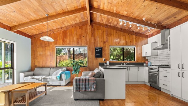 A modern kitchen with white cabinets, a stainless steel oven, and a wooden ceiling. - The Wee Bothy - Onemana Holiday Home (Onemana)
