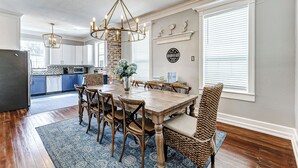 A dining area with a wooden table, wicker chairs, and a chandelier. - Modern Oasis Heated Pool, Spa 6 bedroom walk to beach, restaurants, (Galveston)