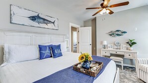 A bedroom with a bed, a ceiling fan, a desk, and a chair. - Modern Oasis Heated Pool, Spa 6 bedroom walk to beach, restaurants, (Galveston)