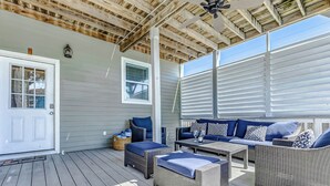 A covered outdoor seating area with wicker furniture and a white door. - Modern Oasis Heated Pool, Spa 6 bedroom walk to beach, restaurants, (Galveston)