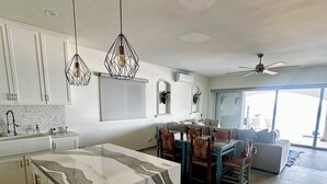 A modern kitchen with a marble island, pendant lights, and a dining area with a table and chairs.