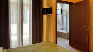 A room with a bed, a television mounted on the wall, and a door leading to a bathroom.