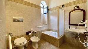 A bathroom with a toilet, bidet, bathtub, and a shower stall.