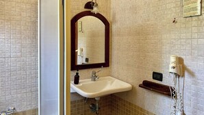 A bathroom with a white sink, a mirror with a wooden frame, and a shower area.