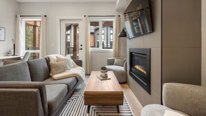 Uma sala de estar moderna com lareira, um conjunto de sofá, uma mesa de centro e uma TV fixada na parede.
