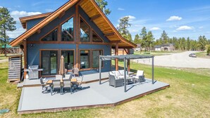 Ein modernes Haus mit einer großen Terrasse, Sitzgelegenheiten im Freien und einer überdachten Veranda.