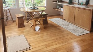 Una cocina con armarios de madera, una mesa de comedor con taburetes, un ventanal con vista a zonas verdes y un horno empotrado.