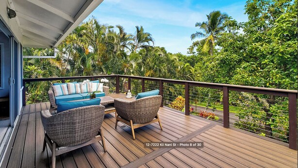 Terraza de madera con mobiliario de mimbre y vistas a la vegetación tropical.