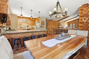 Una cocina rústica con armarios de madera, una zona de bar con taburetes y una mesa de comedor con un mantel individual.