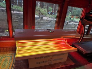 Un sauna avec un intérieur en bois, une fenêtre donnant sur une forêt et un panneau de commande sur le côté.