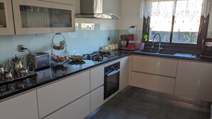 Una cucina moderna con piano cottura a gas, forno integrato, lavello e finestra con tende.