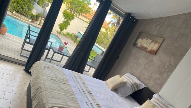Camera d'albergo con un grande letto, vista su una piscina e patio arredato.