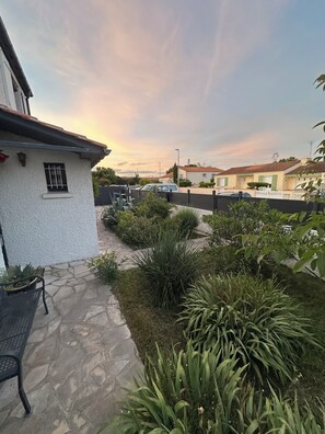Área residencial com um pátio pavimentado, plantas em vasos e vista para as casas vizinhas.
