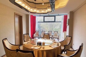 A round table with chairs, a chandelier, and a window with curtains. - ShangHai NvYan Hotel (Shanghai)