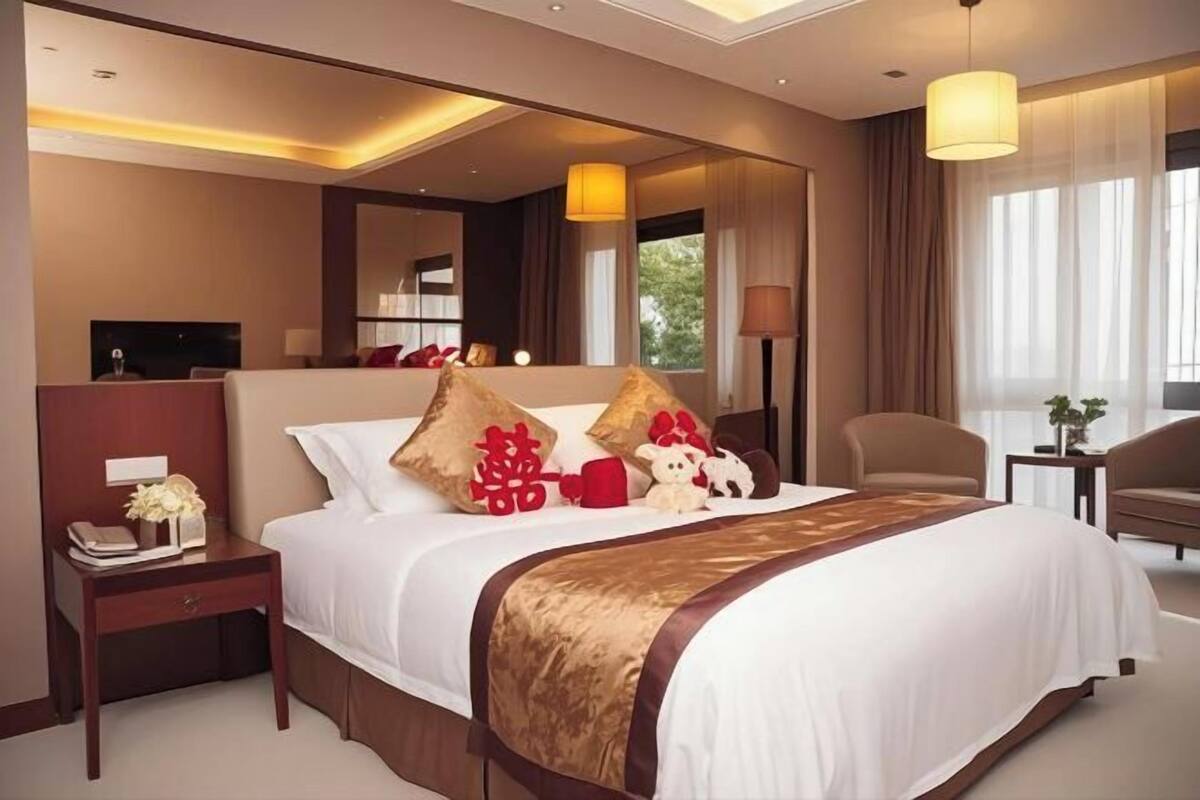 A hotel room with a large bed, bedside tables, a desk, and a chair.