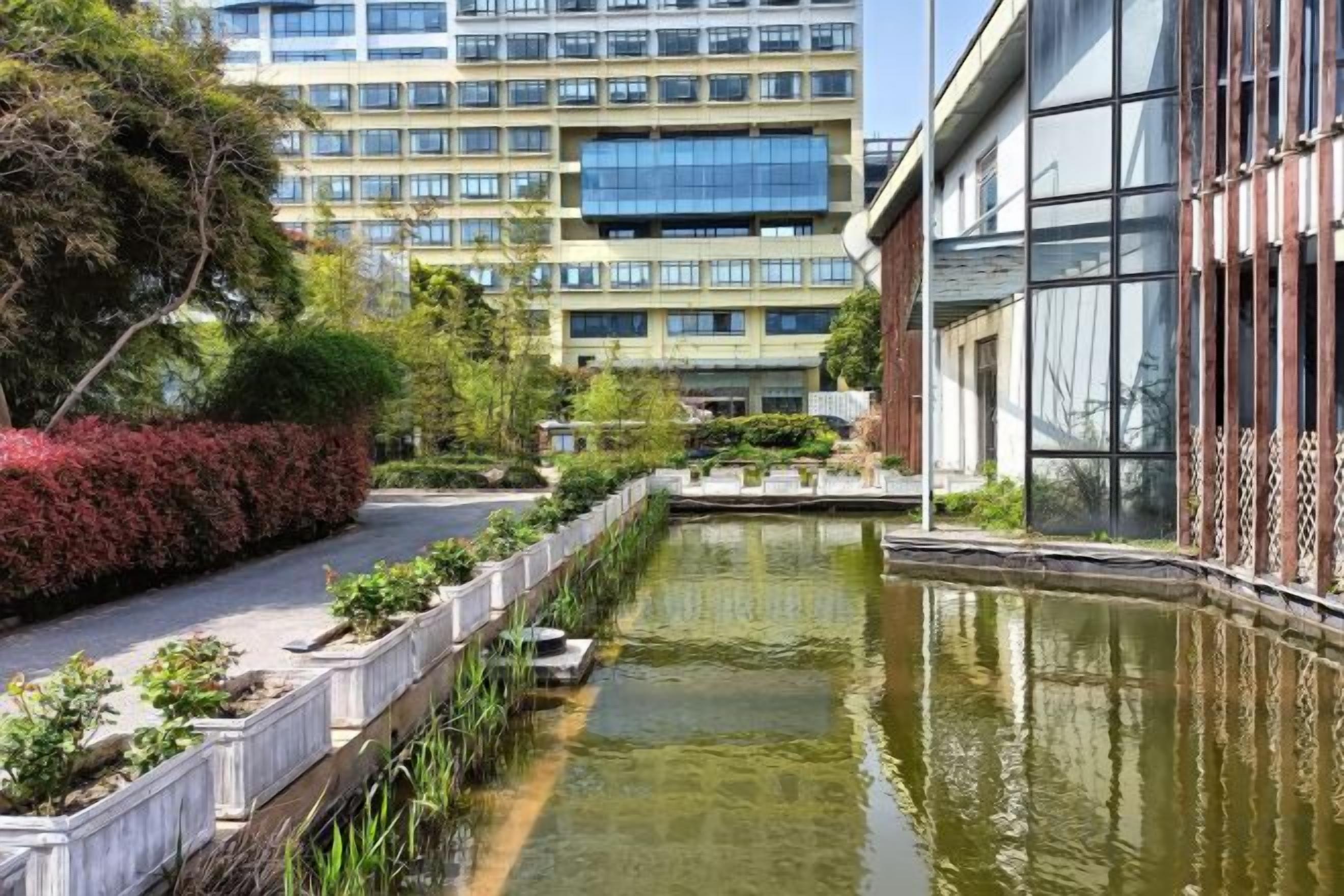 A courtyard with a water feature, surrounded by buildings with large windows and a modern design.