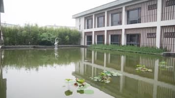 A building with a reflective water feature in front, surrounded by greenery.