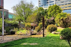 A landscaped garden with a bridge, trees, and a small pavilion. - ShangHai NvYan Hotel (Shanghai)