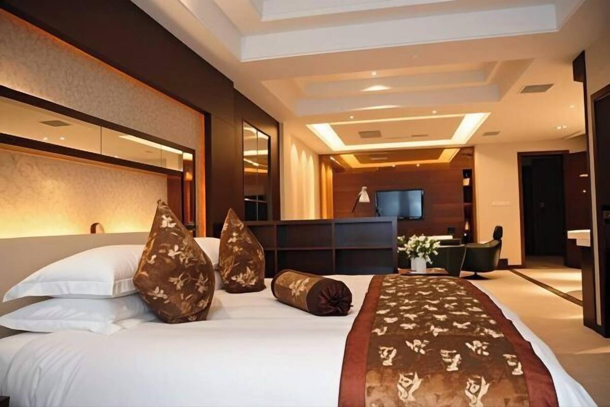 A modern hotel room with a large bed, a desk, and a television.