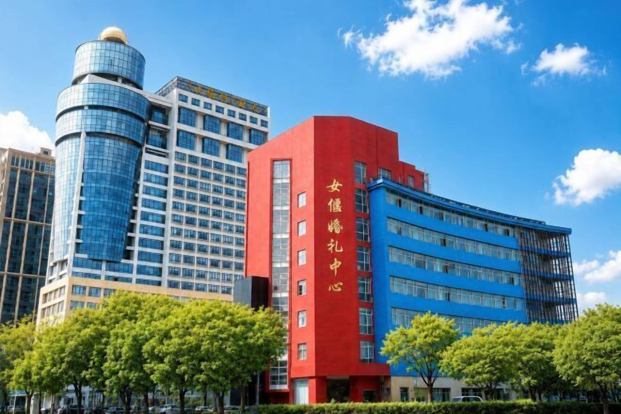 A modern building with a prominent red vertical sign, a blue facade, and a cylindrical glass structure.